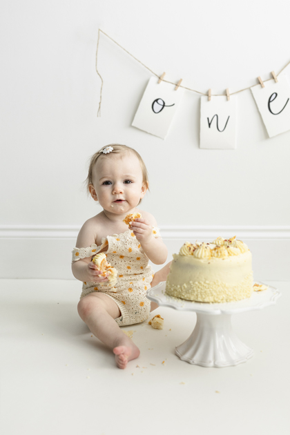 happy toddler eating cake for cake smash birthday celebration